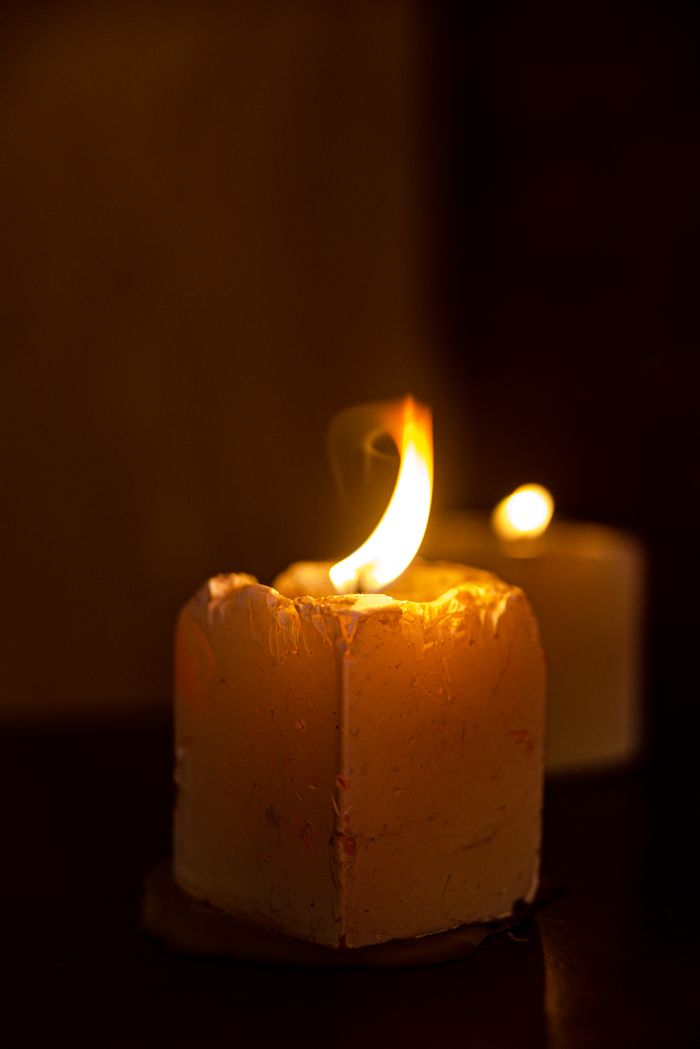 Close-up of wax candles with flickering flames against a dark background, creating a warm atmosphere.