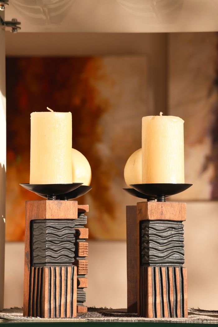 Artistic display of candles on carved wooden holders with abstract background.