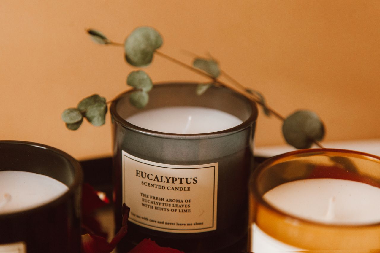 Close-up of eucalyptus scented candles with dried eucalyptus leaves, creating a warm aromatic ambiance.